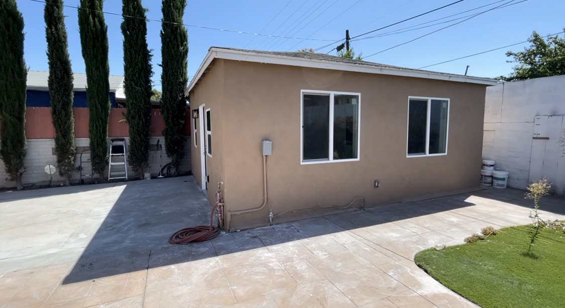 Completed stucco ADU with white trim windows in a Los Angeles backyard