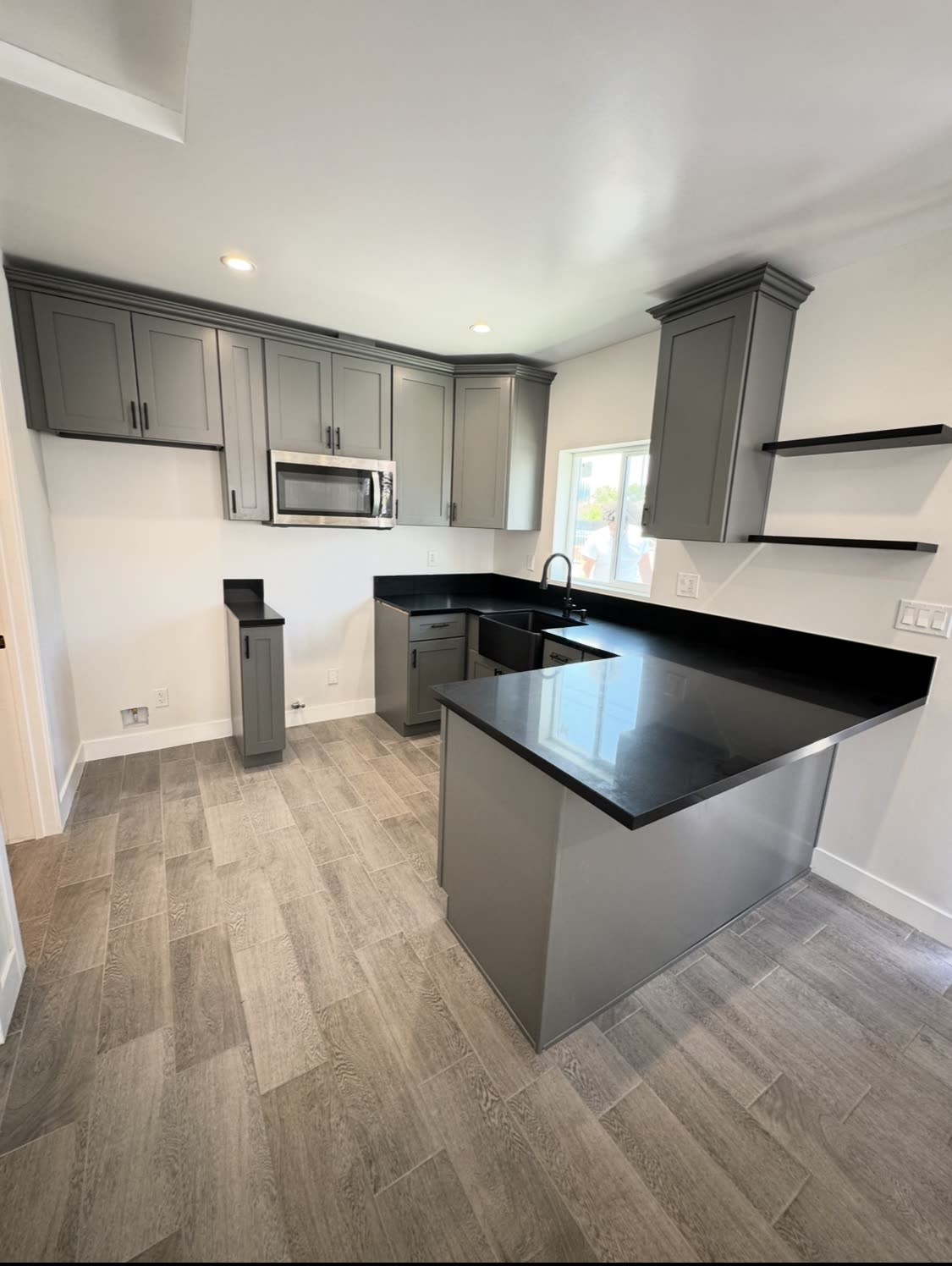 Gray shaker kitchen with black quartz counters and open shelving